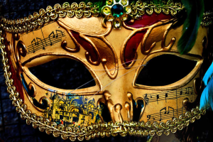 Ein Nahaufnahme eines Karnevalsmasken mit Musiknoten, detaillierten Designs und Federn, mit einem unscharfen Hintergrund.