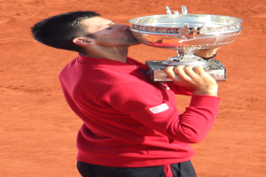 Novak Djokovic hält den French-Open-Pokal nach seinem Sieg gegen Rafael Nadal im Finale der Herren-Einzel, feiert mit triumphaler Miene.