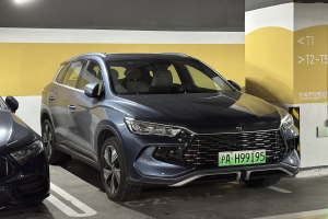 Zwei Autos nebeneinander in einer Garage mit einer Wand und einer Deckenbeleuchtung im Hintergrund, begleitet von einer Texttafel auf der rechten Seite.
