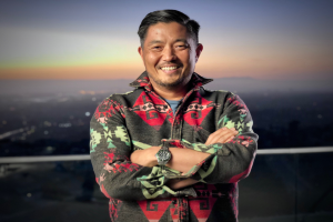 David Chang, Gründer und CEO, steht auf einem Dach mit verschränkten Armen, lachend, mit einer Uhr, vor einem unscharfen Hintergrund.