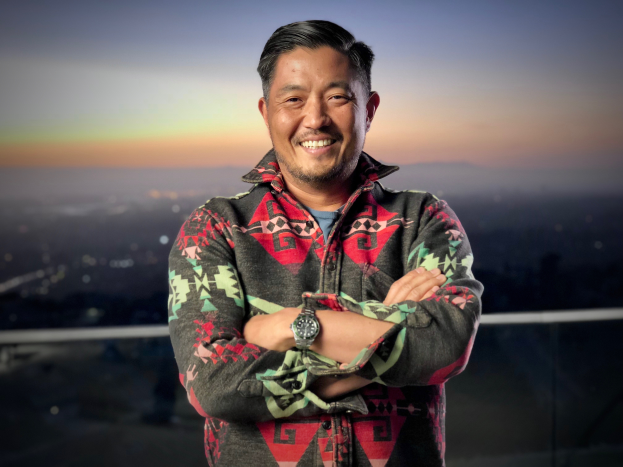 David Chang, Gründer und CEO, steht auf einem Dach mit verschränkten Armen, lachend, mit einer Uhr, vor einem unscharfen Hintergrund.