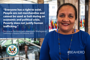 Eine Frau in einem blauen Kleid steht lächelnd vor einem Gebäude mit einem Zitat über Menschenrechte, mit Menschen, Pflanzen und Flaggen im Hintergrund und einem Logo und Text auf der linken Seite.