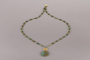 Eine goldene Kette mit einem grünen Davidstern-Anhänger mit einem Türkisstein, der auf einer flachen Oberfläche liegt.