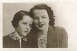 Ein altes Schwarz-Weiß-Foto einer Mutter und Tochter, die in die Kamera lächeln.