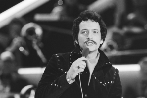 Elvis Presley in einem Schwarz-Weiß-Foto hält ein Mikrofon während einer Live-Aufführung, mit einem unscharfen Hintergrund.