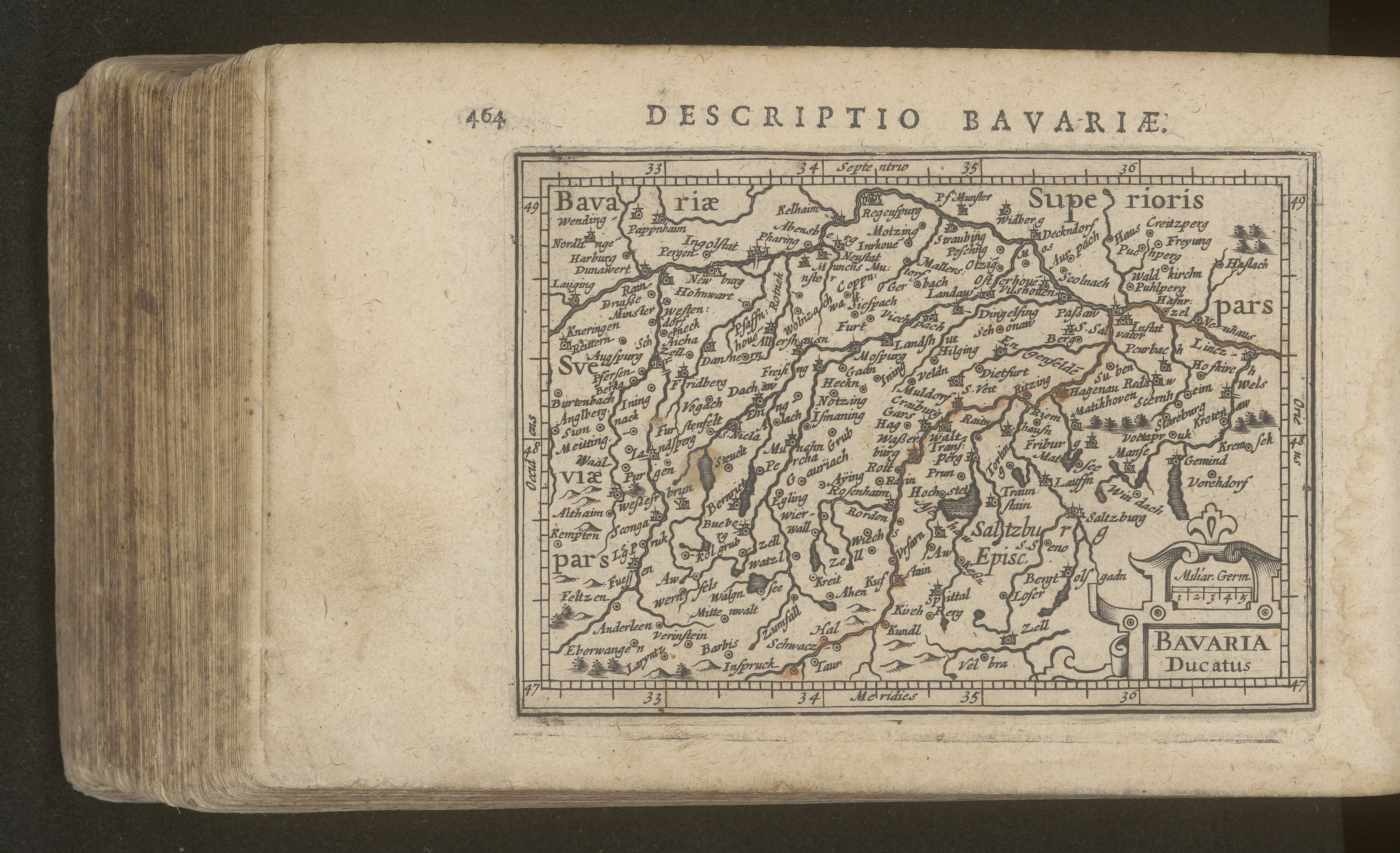 Altes Buch mit einer detaillierten Karte von Bayern vor einem schwarzen Hintergrund, die geografische Merkmale zeigt.