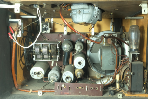 Ein Nahaufnahme eines altmodischen Verstärkers in einem Holzgehäuse mit verschiedenen elektronischen Geräten und Kabeln, die damit verbunden sind.