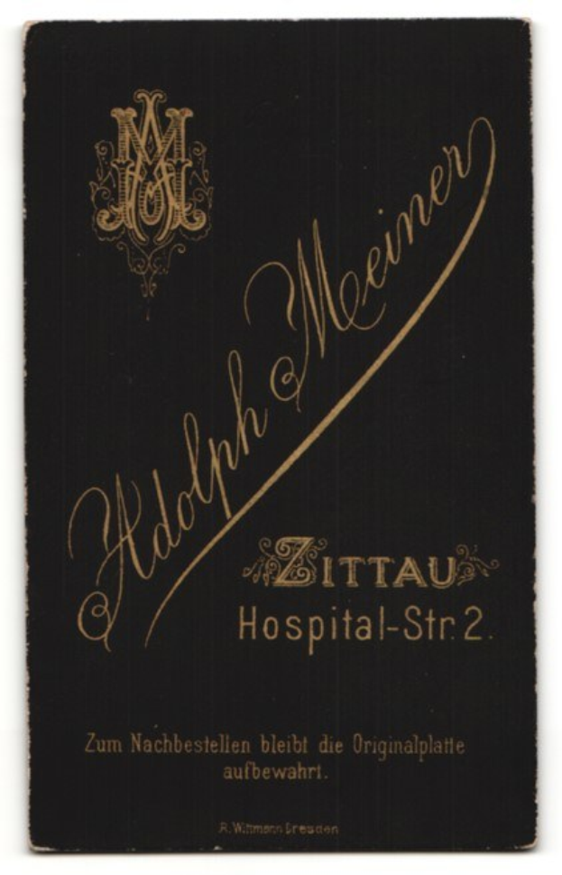 Schwarzes Buch mit goldener Schrift, das "Adolph Meiner - Zittau Hospital-Str 2" auf einem weißen Hintergrund liest.