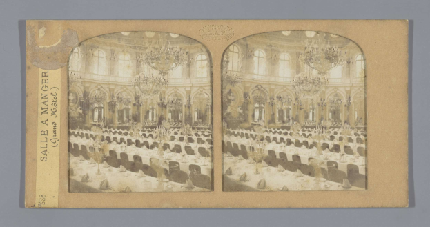 Ein altes Foto eines prächtigen Hotel-Speisesaals mit Tischen, Stühlen, Kronleuchtern und Fenstern, das den Text "Sale a Manger, Grand Hotel" links zeigt.