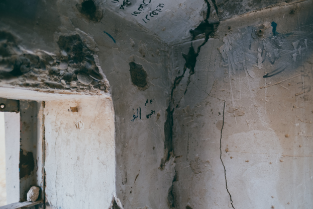 Ein Raum mit einem Fenster auf der linken Seite und einer Wand mit einem durchlaufenden Riss, bedeckt mit Graffiti.
