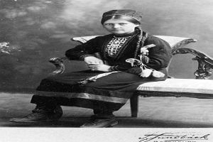 Ein altes Schwarz-Weiß-Foto einer Frau in traditioneller Kleidung, die friedlich mit geschlossenen Augen und auf dem Schoß ruhenden Händen dasitzt, mit einem unscharfen, verträumten Hintergrund.