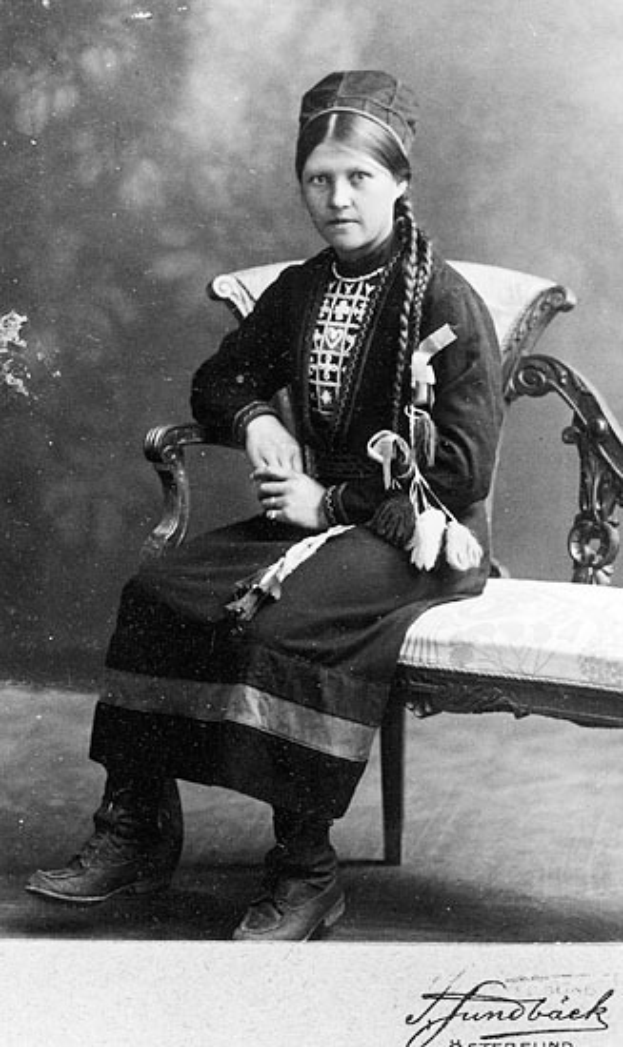 Ein altes Schwarz-Weiß-Foto einer Frau in traditioneller Kleidung, die friedlich mit geschlossenen Augen und auf dem Schoß ruhenden Händen dasitzt, mit einem unscharfen, verträumten Hintergrund.