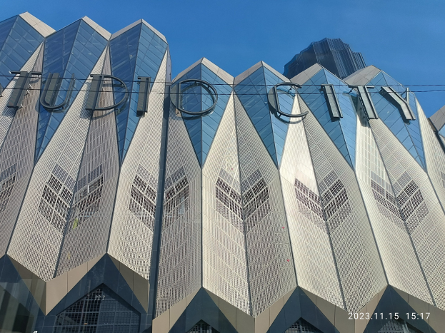 Ein hohes Gebäude mit "studio city"-Text darauf, umgeben von Drähten vor einem Himmel-Hintergrund, mit einem Wasserzeichen.