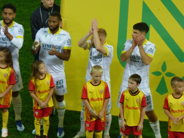 Gruppe von Fußballspielern in Uniformen, die auf einem Ligue 1-Feld jubeln.