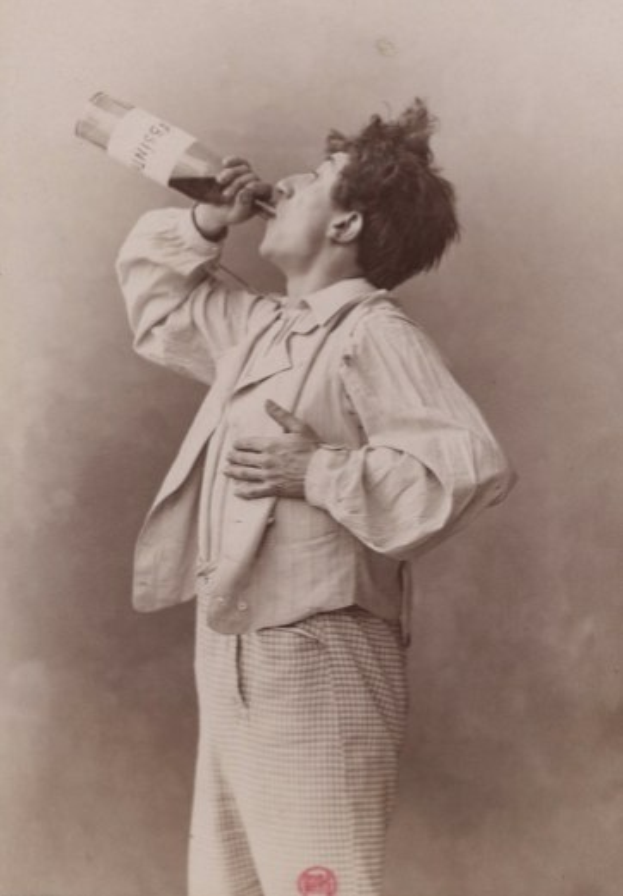 Ein altes Schwarz-Weiß-Foto eines Mannes mit ernstem Gesichtsausdruck, der aus einer Flasche trinkt.