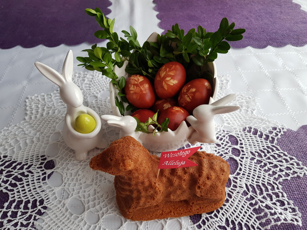 Ein mit einer Decke drapierter Tisch hält eine Schüssel voller bunter Oster-Eier mit Osterhasen-Figuren darauf.